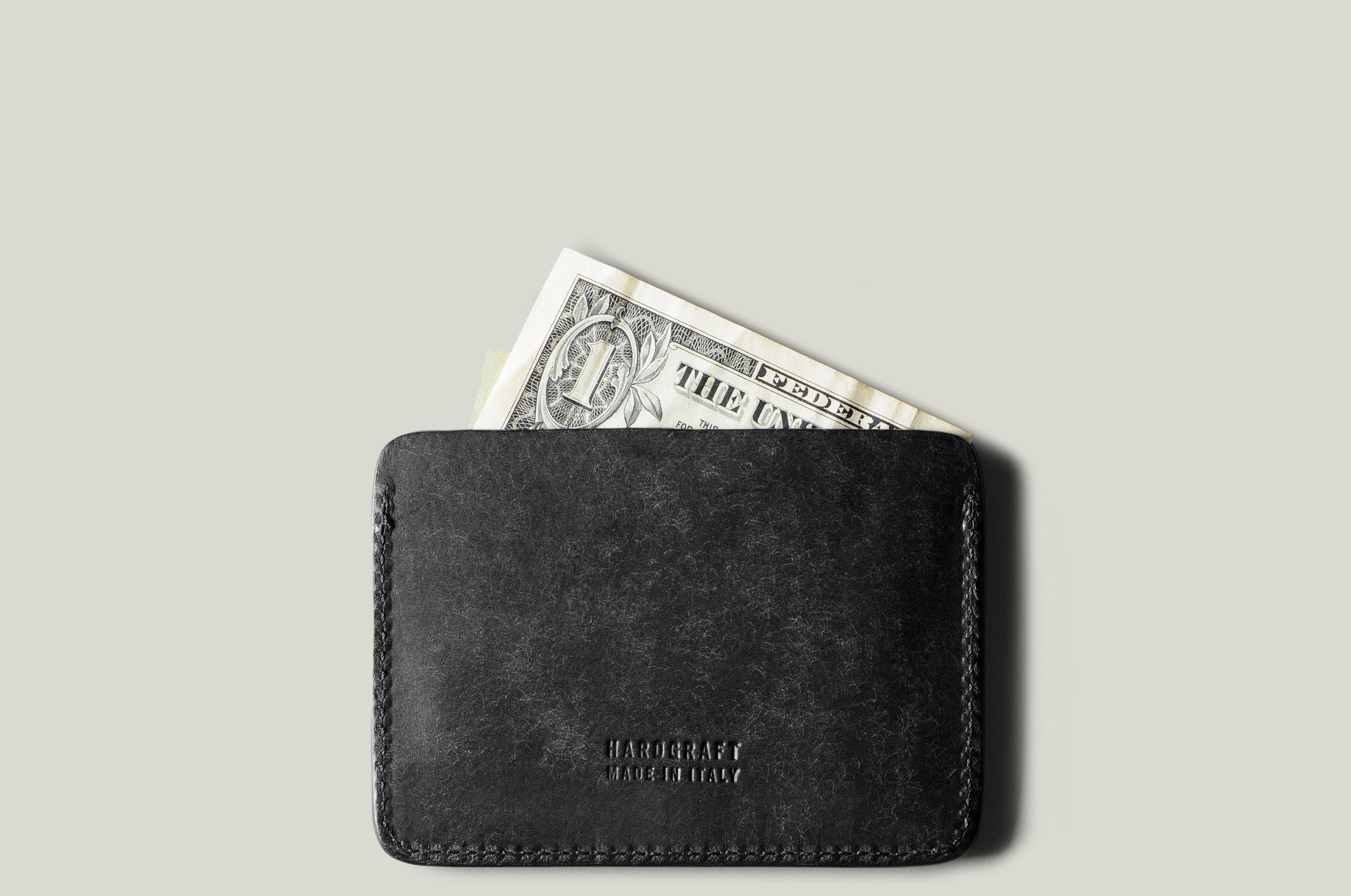 Black leather card case with a dollar bill on a gray background