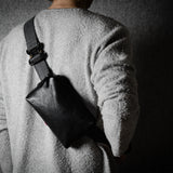 Person wearing a black shoulder bag on a dark background