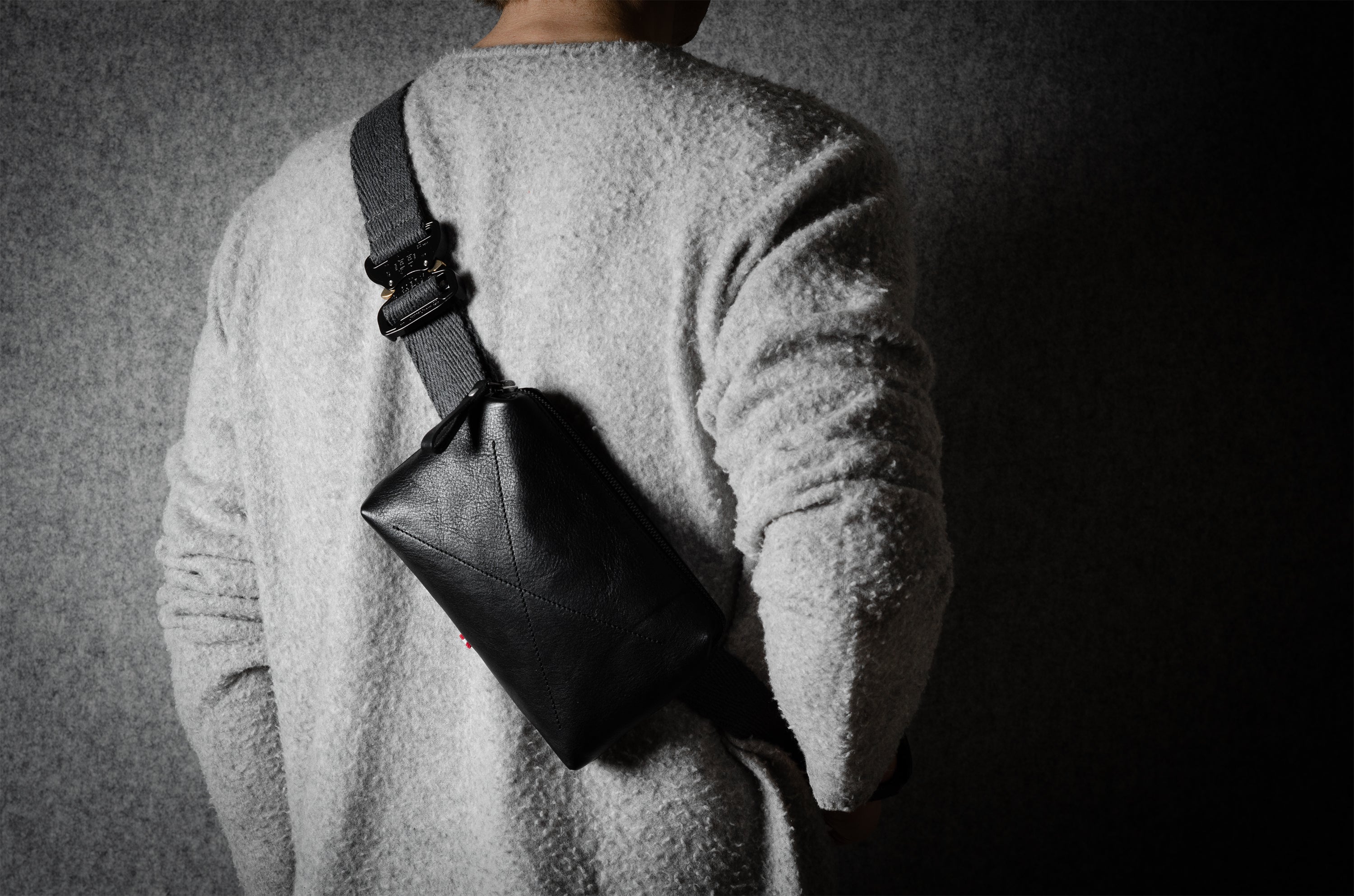 Person wearing a black shoulder bag on a dark background