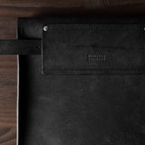 Black leather bag with a brand logo on a wooden surface