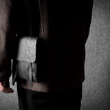 Person holding a black  leather bag against a gray background