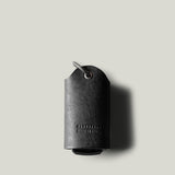 Black leather key holder with keyring on light grey background