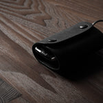 Black leather key holder with 2 metal buttons  on wood background