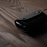 Black leather key holder with 2 metal buttons  on wood background