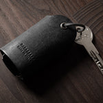 Black leather key holder showing keys on wood background