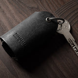 Black leather key holder showing keys on wood background