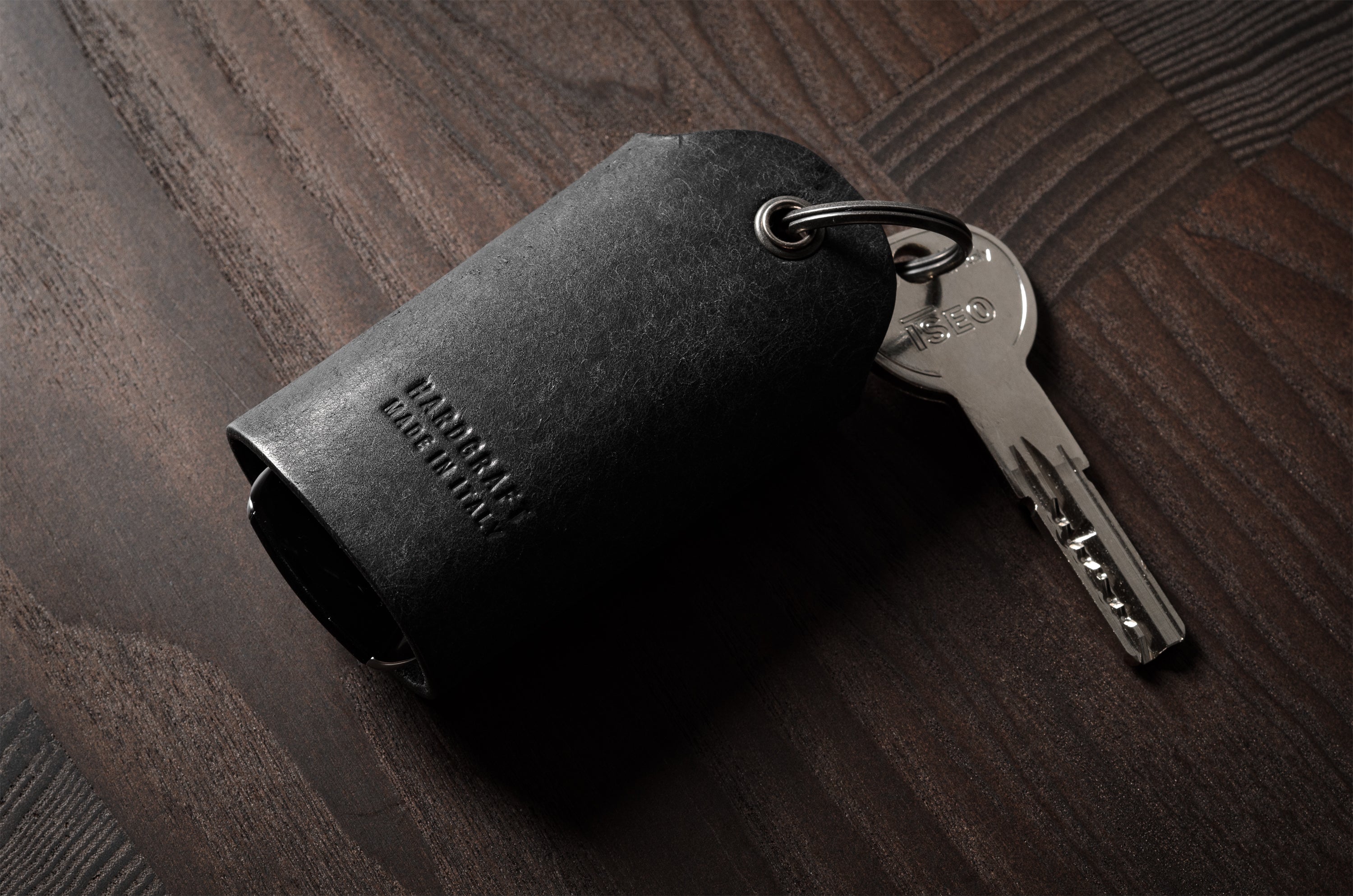 Black leather key holder showing keys on wood background