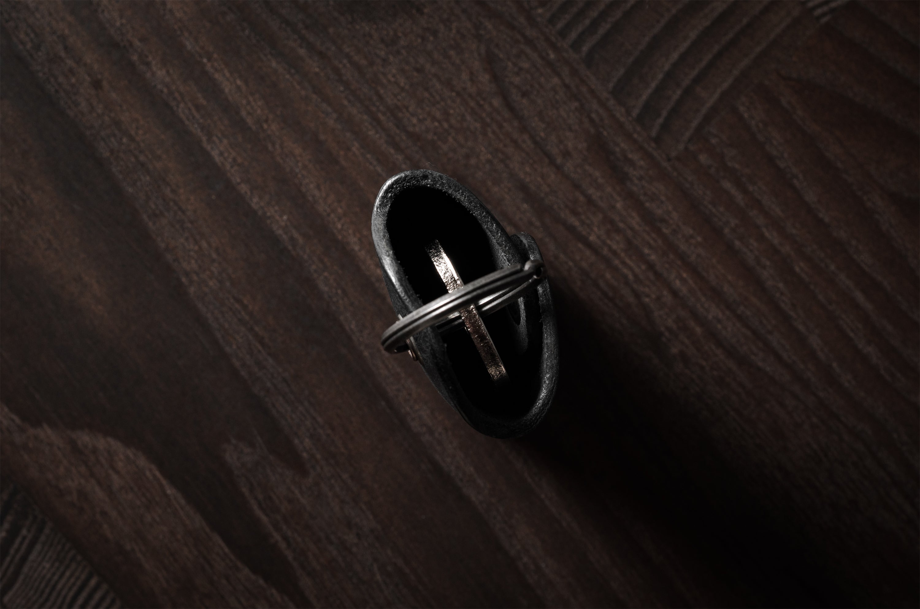 Black leather key holder with keyring on wood background