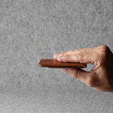 Hand holding a brown leather wallet against a gray background