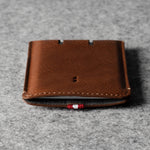 Brown leather cardholder on a gray textured background
