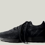 A single black suede sneaker with laces, set against a white background.