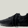 A single black suede sneaker with laces, set against a white background.