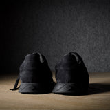 Black suede sneakers on a grey and brown wood background.