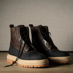 Pair of black and brown hiking boots on a wooden floor with a neutral background