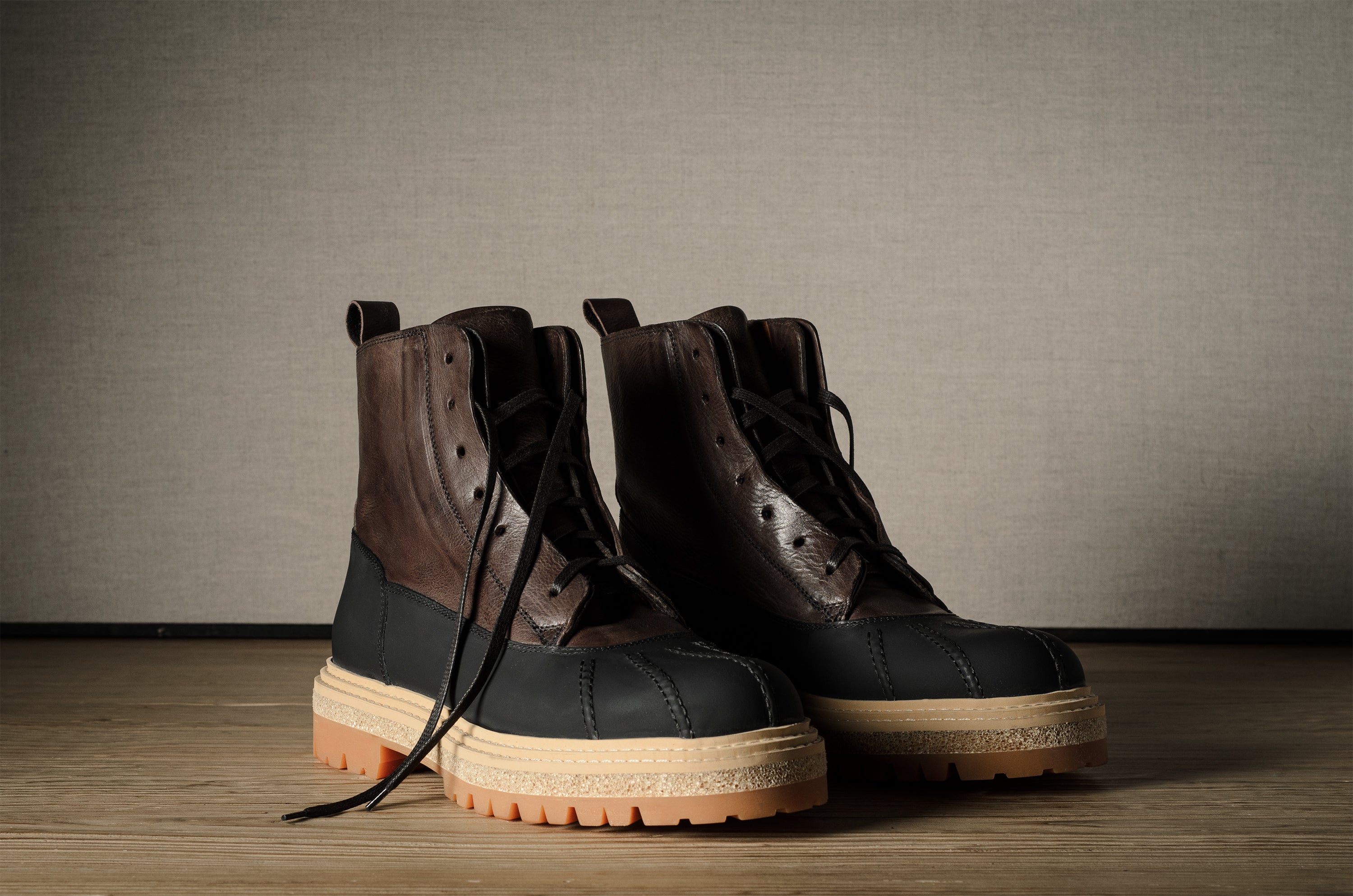 Pair of black and brown hiking boots on a wooden floor with a neutral background