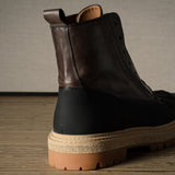 Brown leather hiking boot with a black sole on a wooden floor