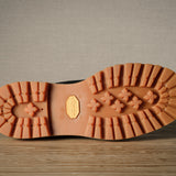Close-up of a brown hiking sole with tread pattern on a wooden surface.