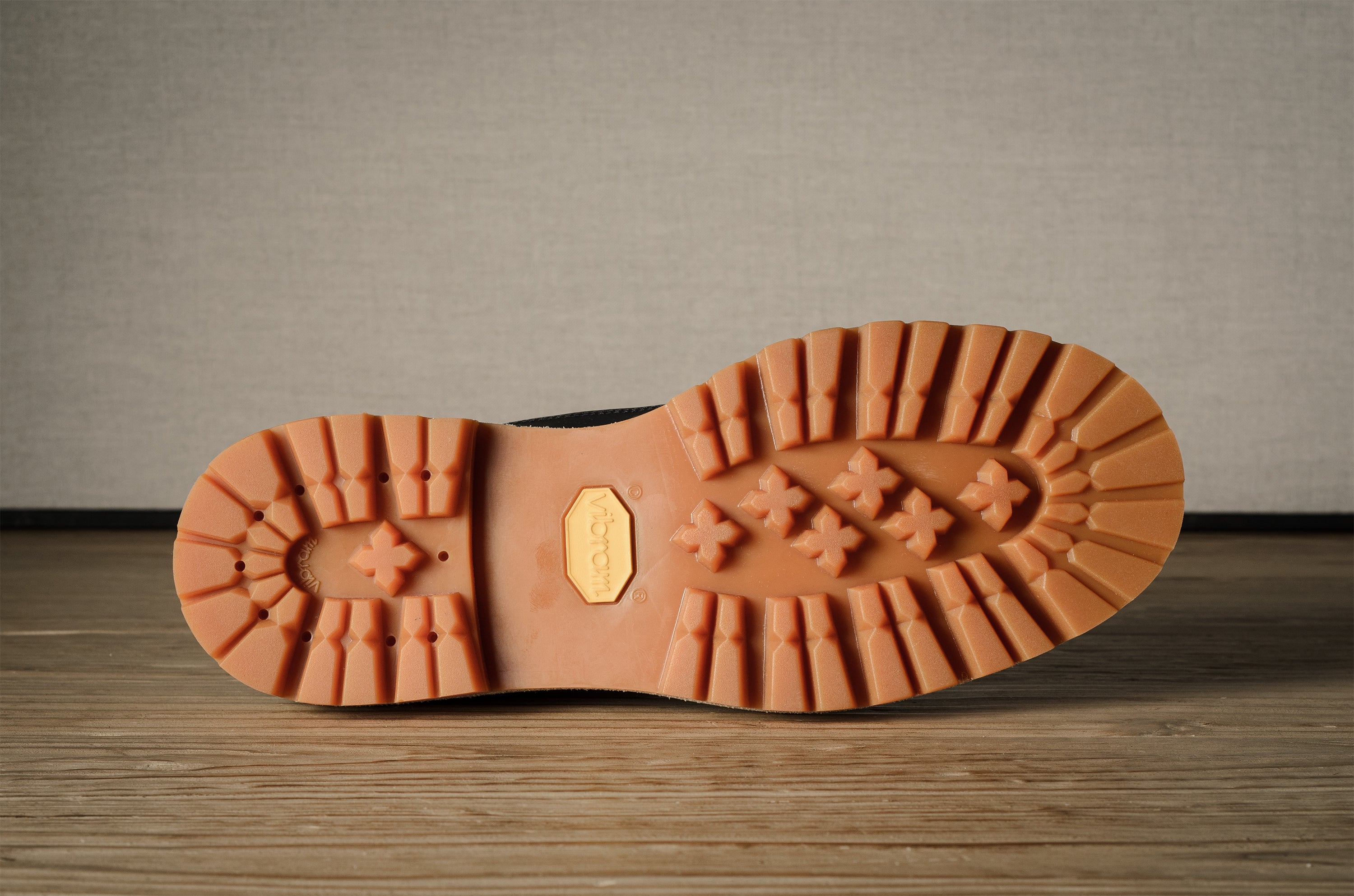 Close-up of a brown hiking sole with tread pattern on a wooden surface.