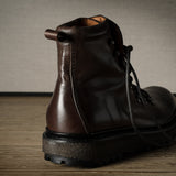 Brown leather boot on a wooden surface with a neutral background
