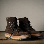 Pair of brown leather boots on a wooden floor with a neutral background