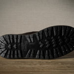 Close-up of a black boot sole with brand logo on a wooden surface.