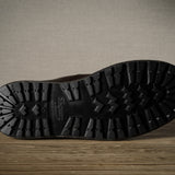 Close-up of a black boot sole with brand logo on a wooden surface.