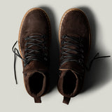 Pair of brown suede boots on a light gray background