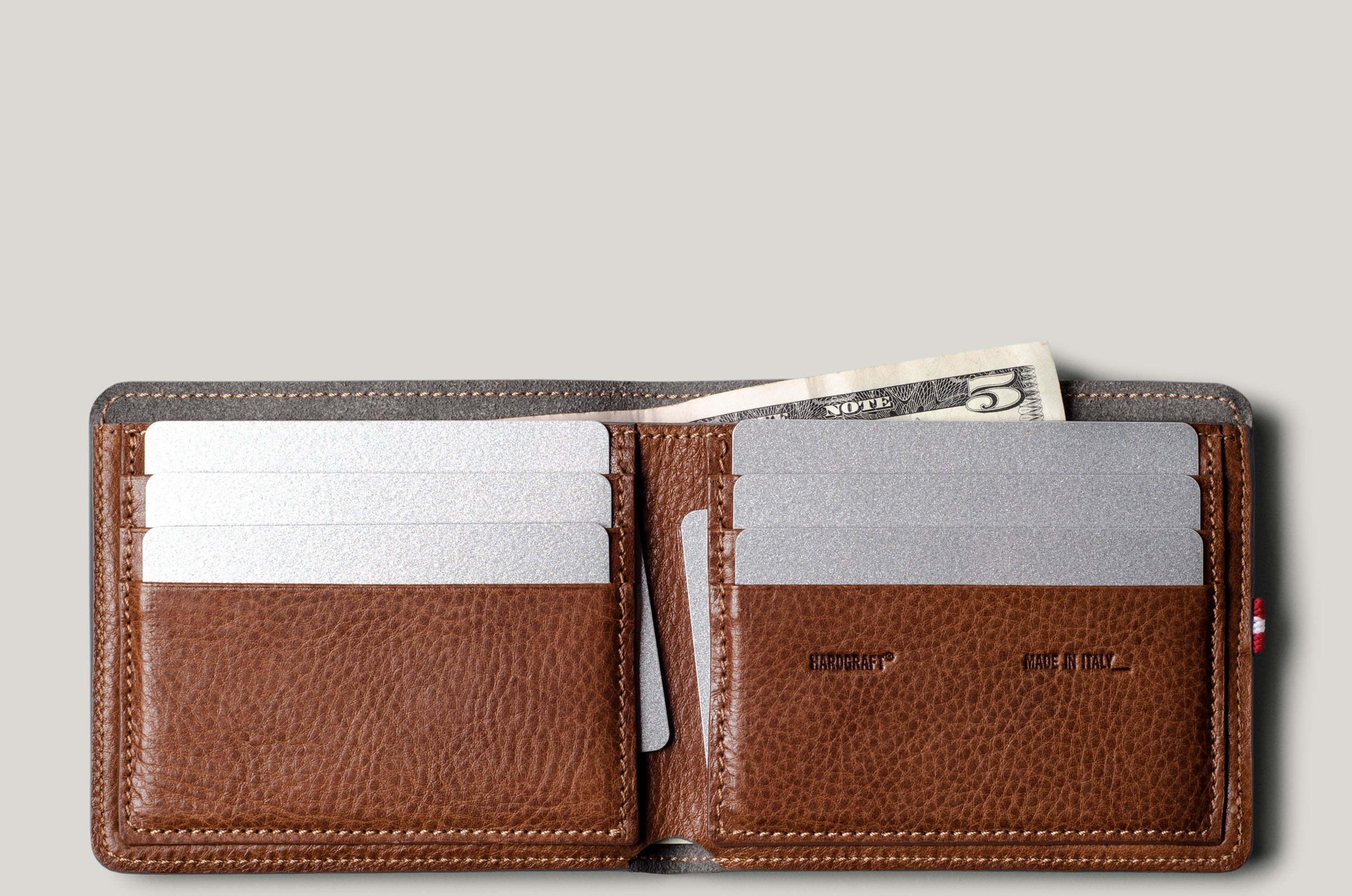 Brown leather wallet with card slots and money pocket on a light gray background