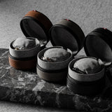Three open leather watch cases on a marble surface