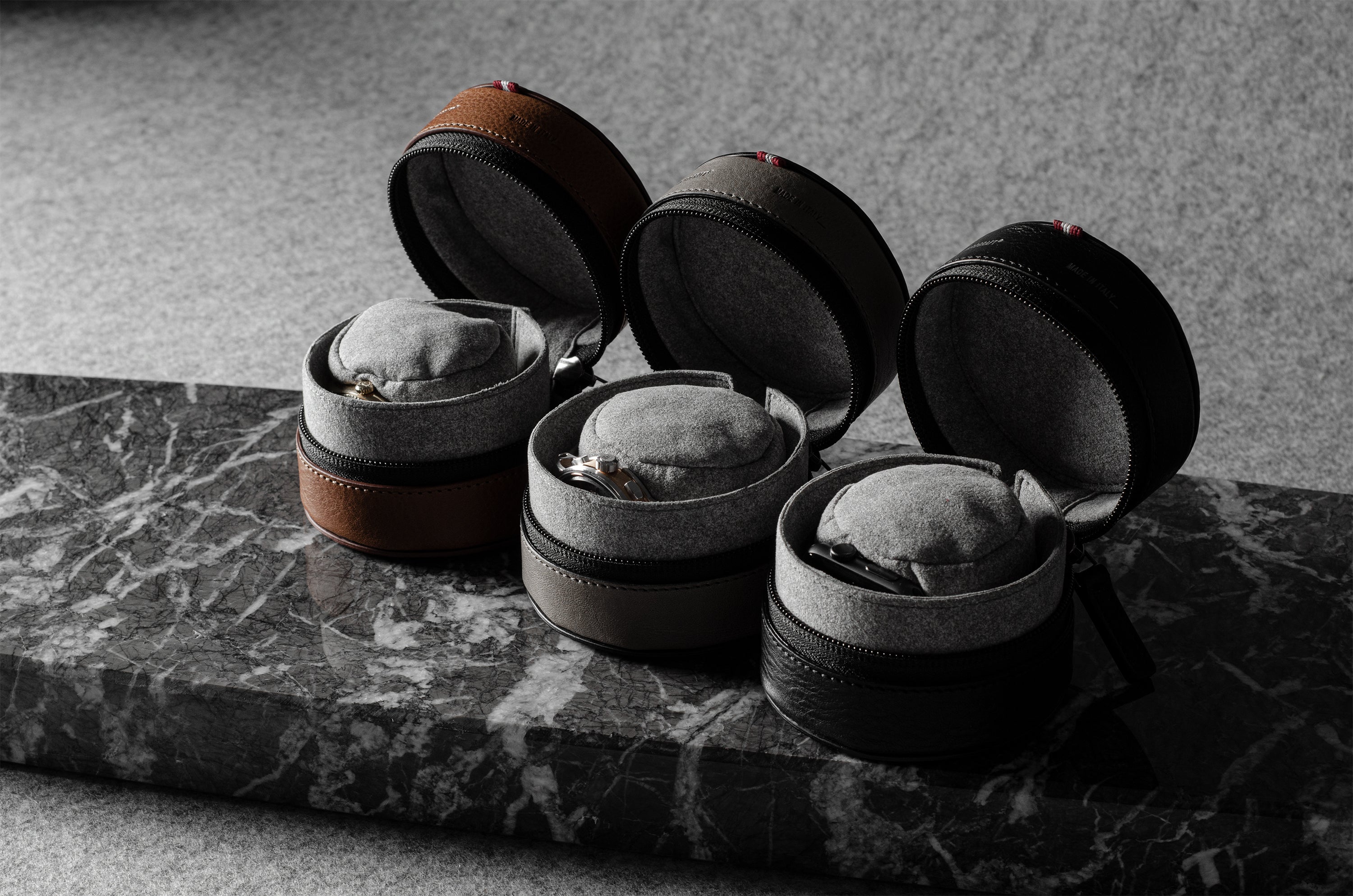 Three open leather watch cases on a marble surface