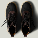 Pair of black leather hiking boots with brown soles on a light gray background