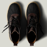 Pair of black leather hiking boots with brown soles on a light gray background