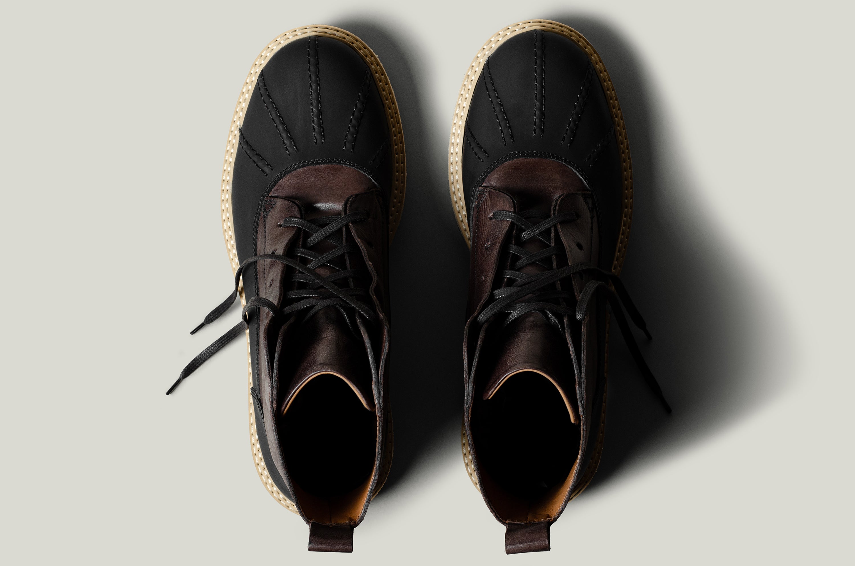 Pair of black leather hiking boots with brown soles on a light gray background
