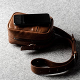 A classic brown leather shoulder bag with a zipper closure and an adjustable strap