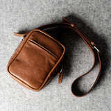 A classic brown leather shoulder bag with a zipper closure and an adjustable strap