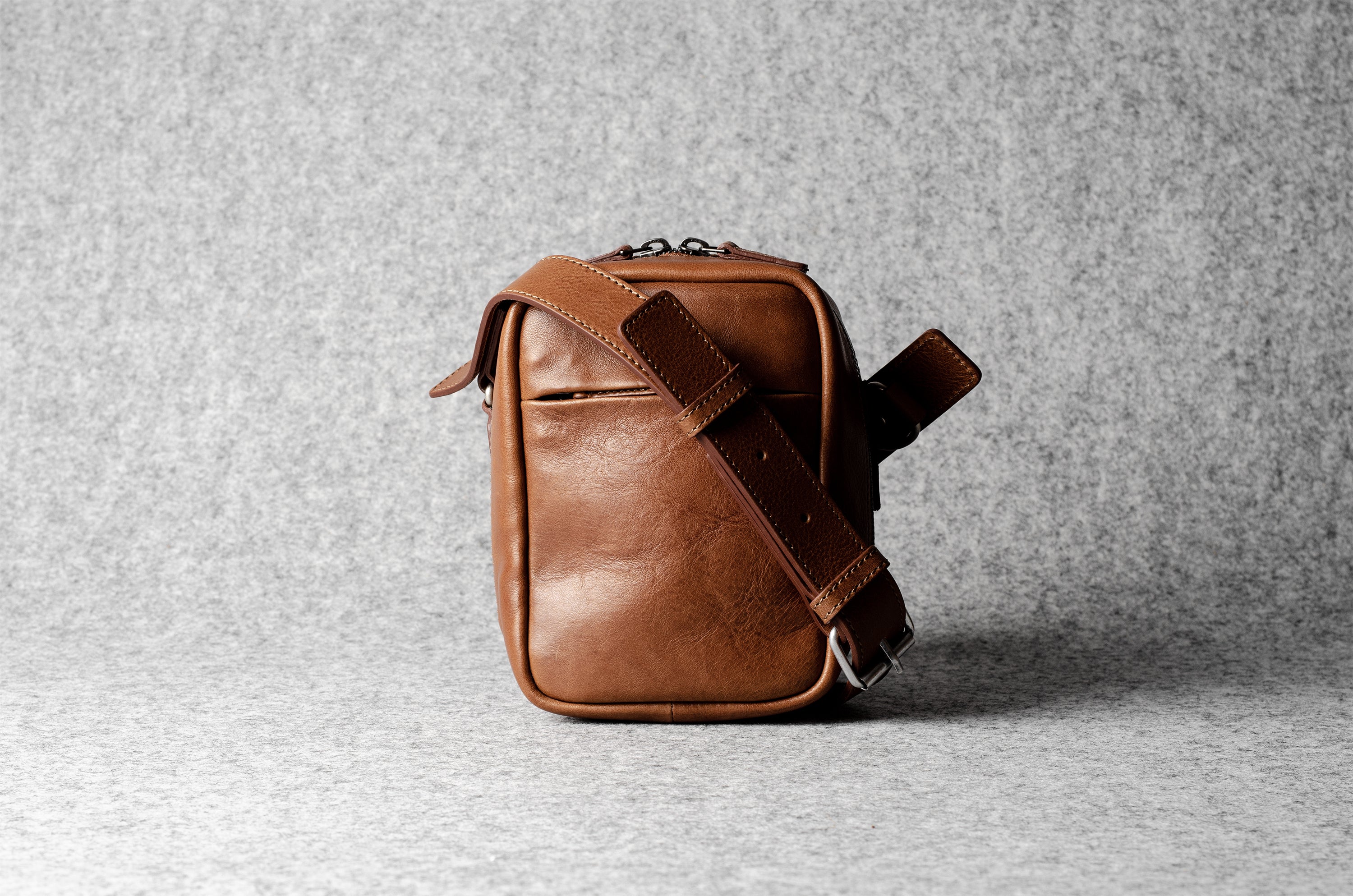 A classic brown leather shoulder bag with a zipper closure and an adjustable strap