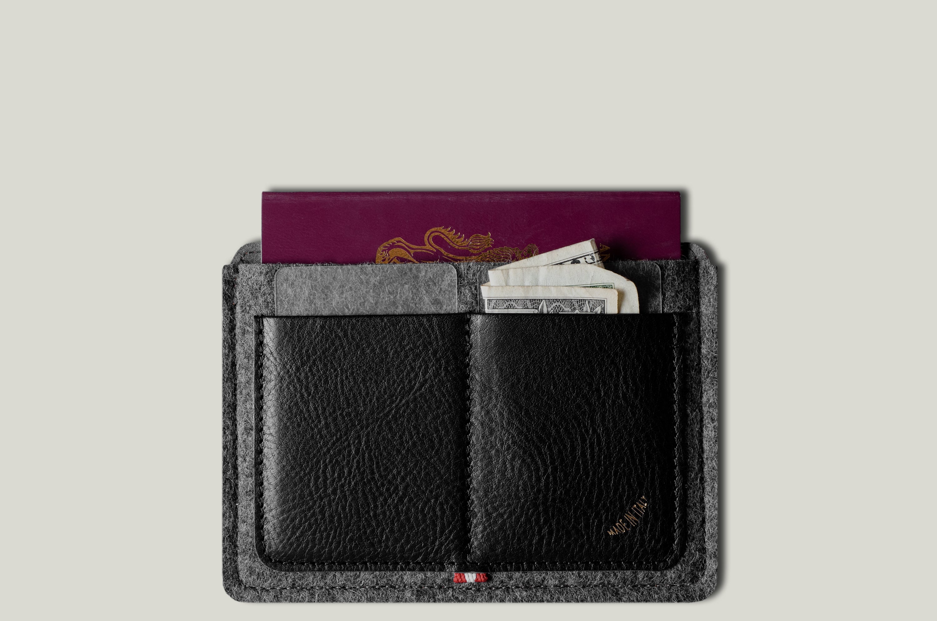 Black wallet with gray exterior holding a passport and money on a light gray background