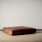 Brown leather bag with X detail and shoulder strap.