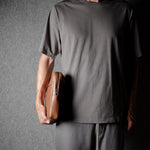 Brown leather bag with X detail and shoulder strap.