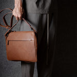 Brown leather bag with X detail and shoulder strap.
