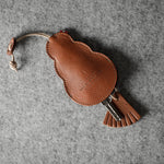 Brown leather keypouch with a leather string on a gray background