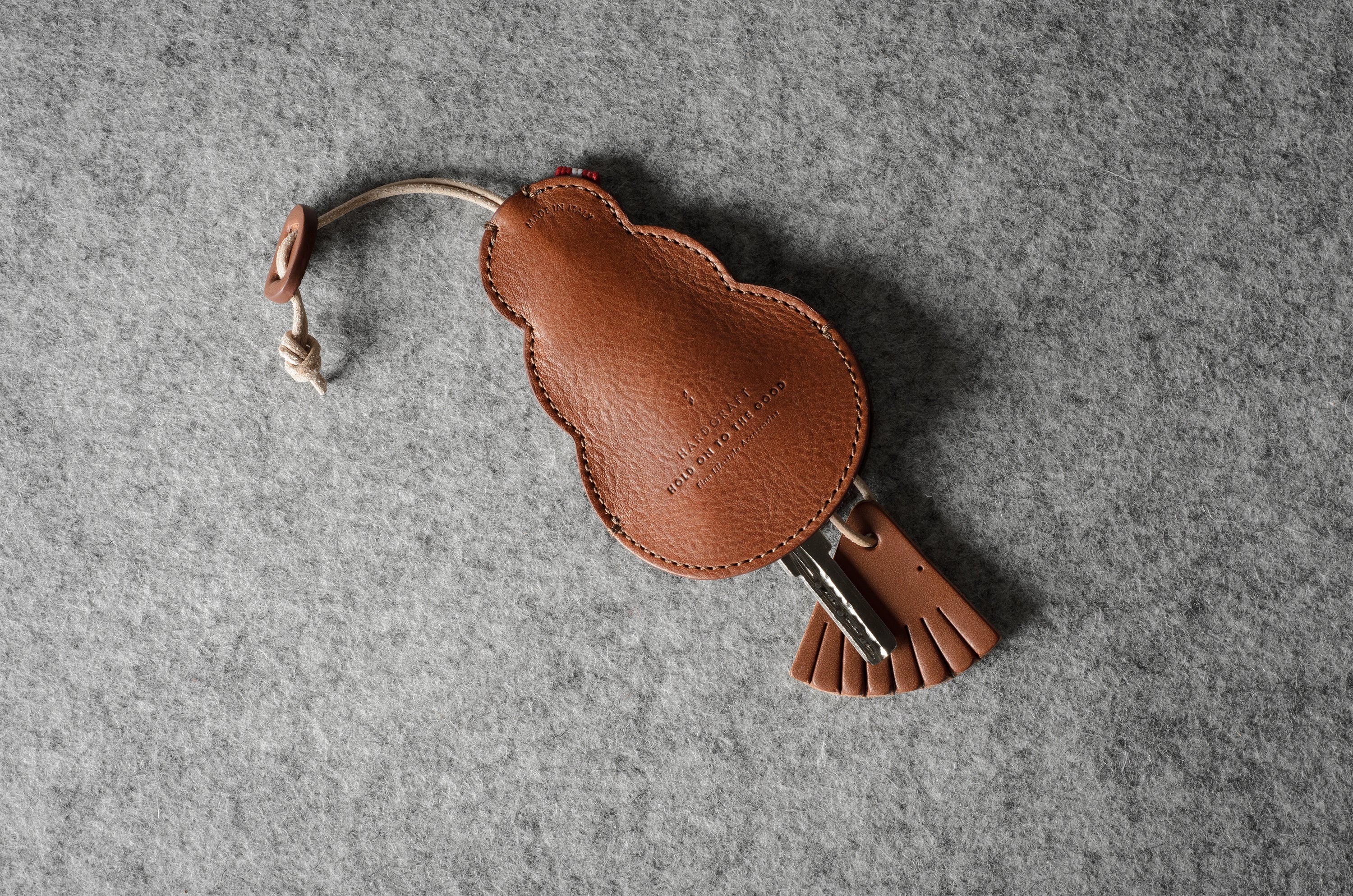 Brown leather keypouch with a leather string on a gray background
