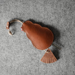 Brown leather keypouch with a leather string on a gray background