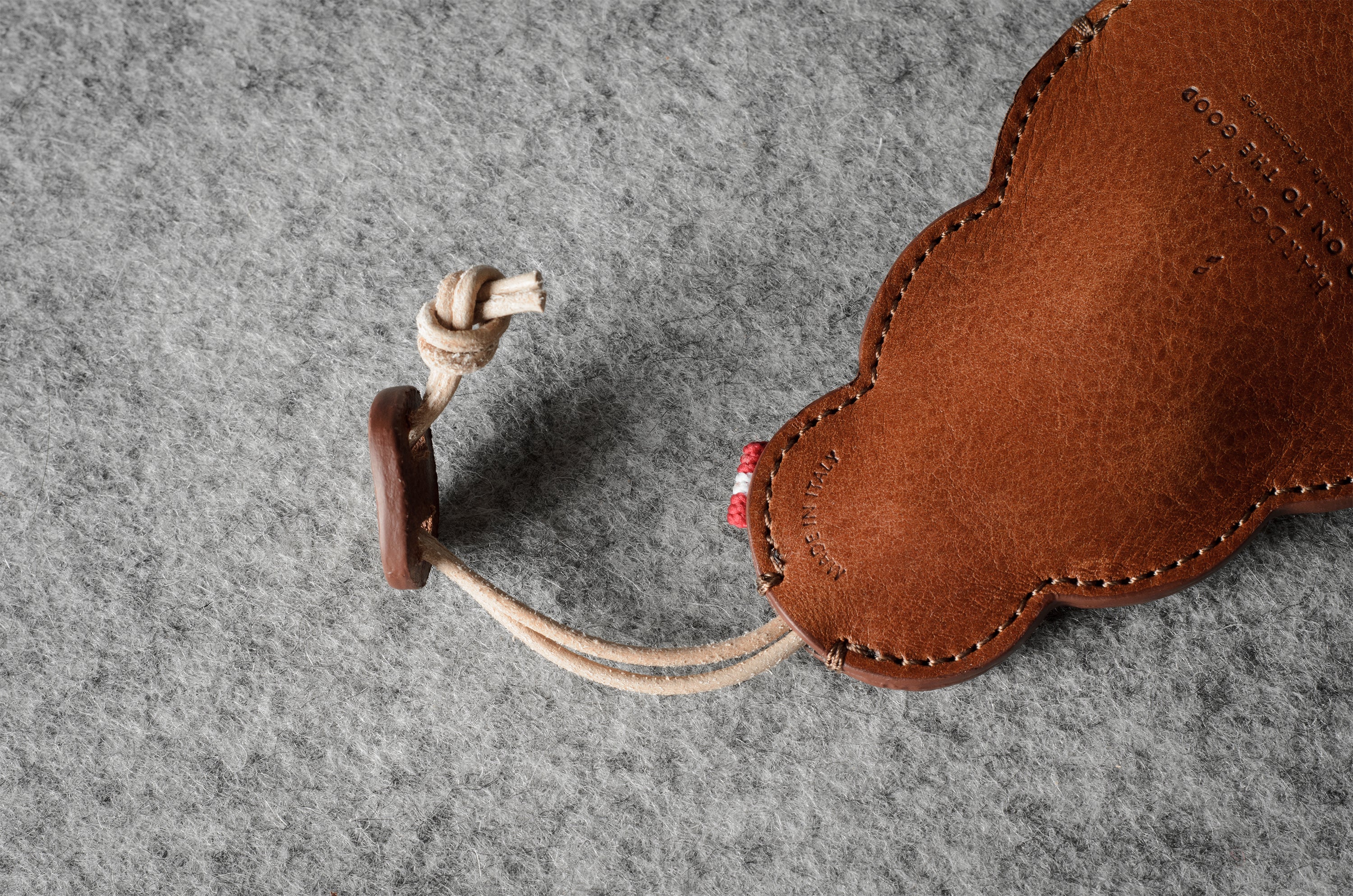 Brown leather keypouch with a leather string on a gray background.
