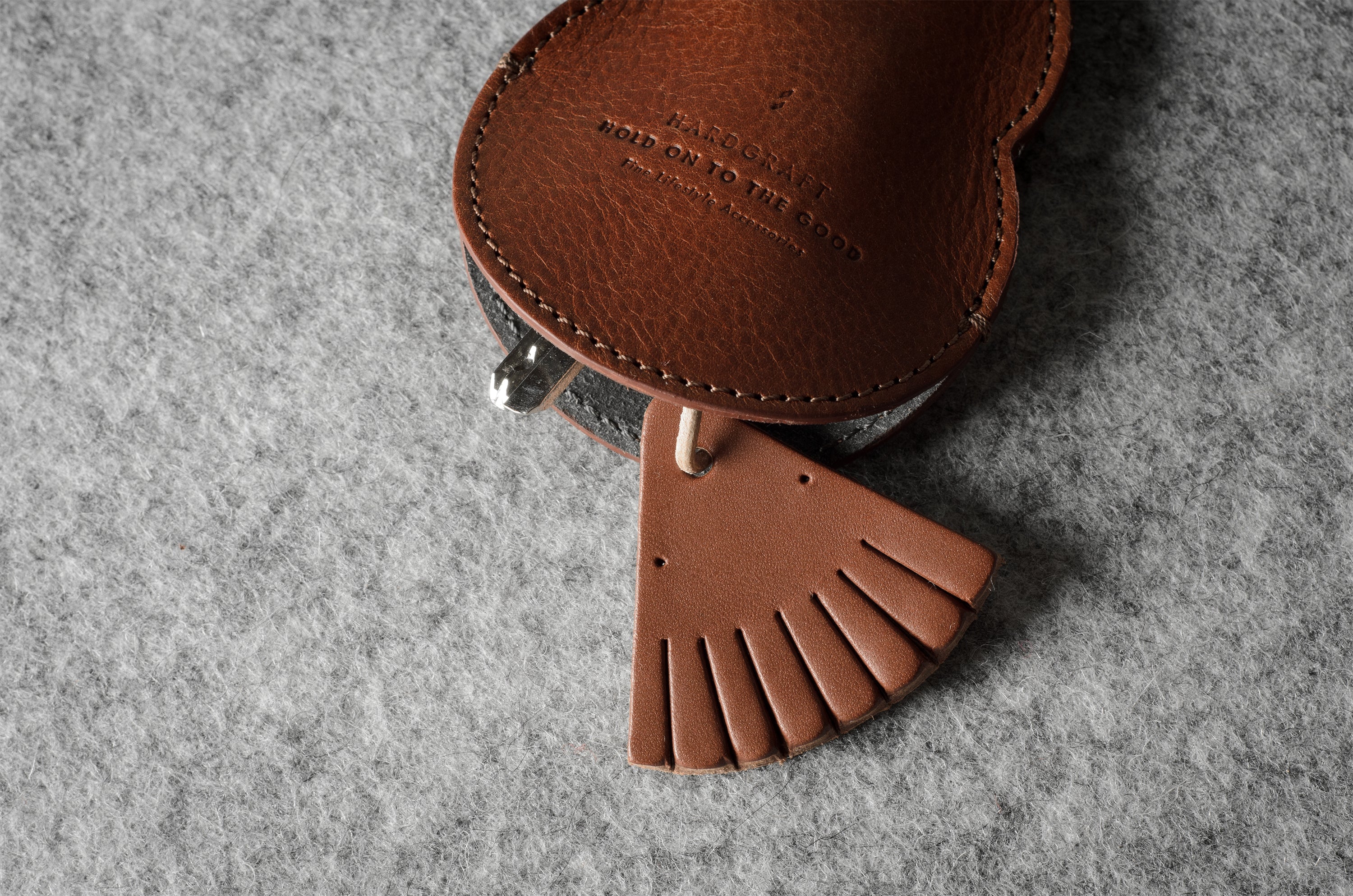 Brown leather keypouch with a leather string on a gray background