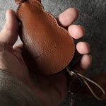 Brown leather keypouch with a leather string on a gray background