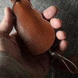 Brown leather keypouch with a leather string on a gray background