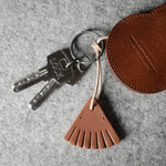Brown leather keypouch with a leather string on a gray background