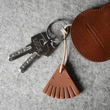 Brown leather keypouch with a leather string on a gray background