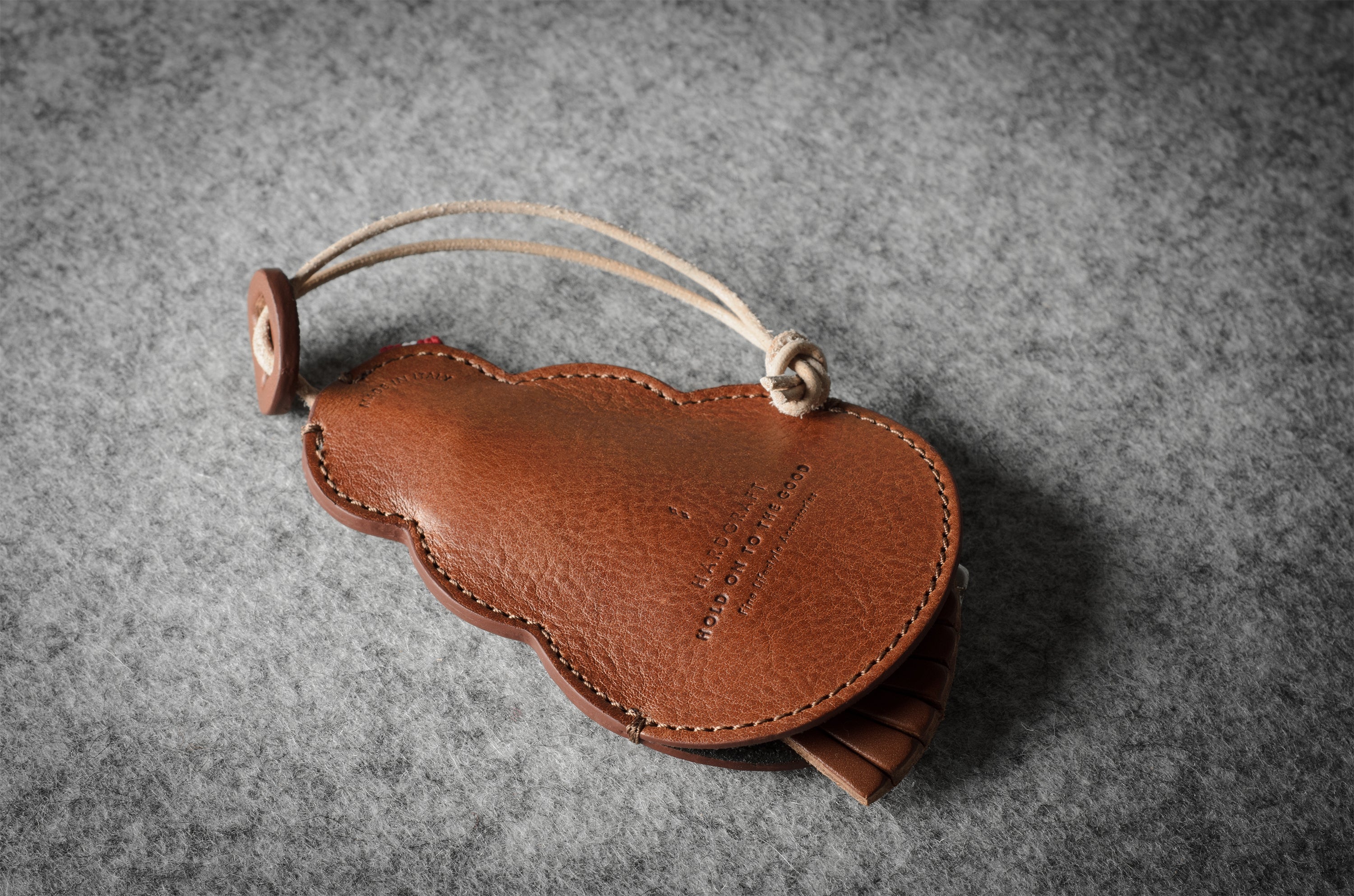 Brown leather keypouch with a leather string on a gray background